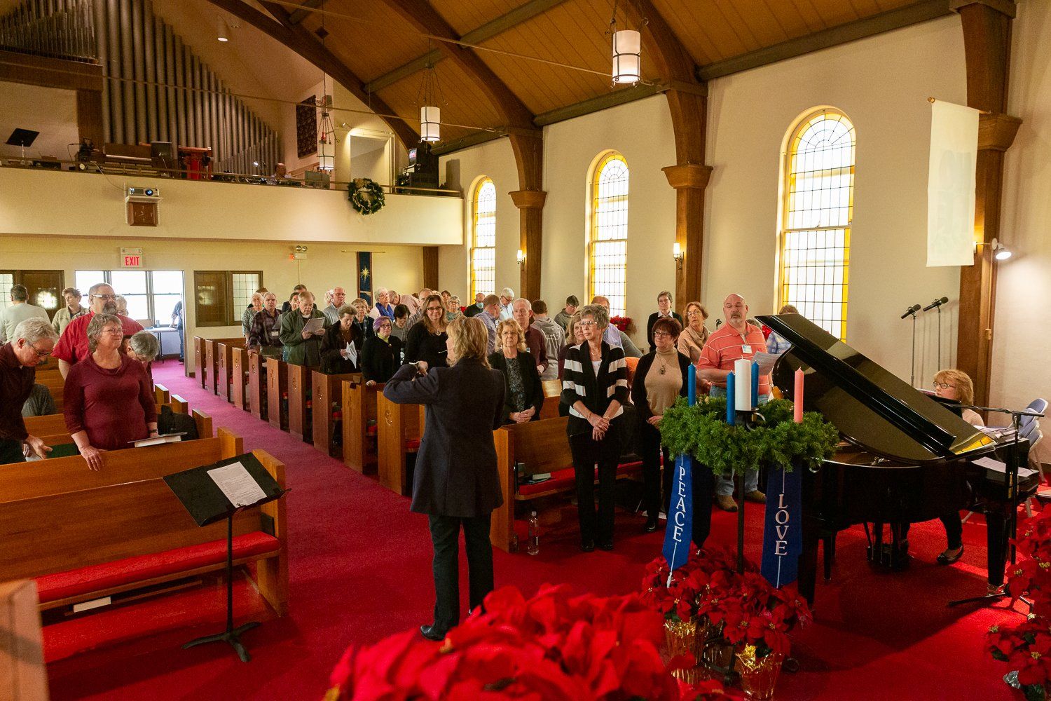 A group of people are singing in a church with a piano in the background.