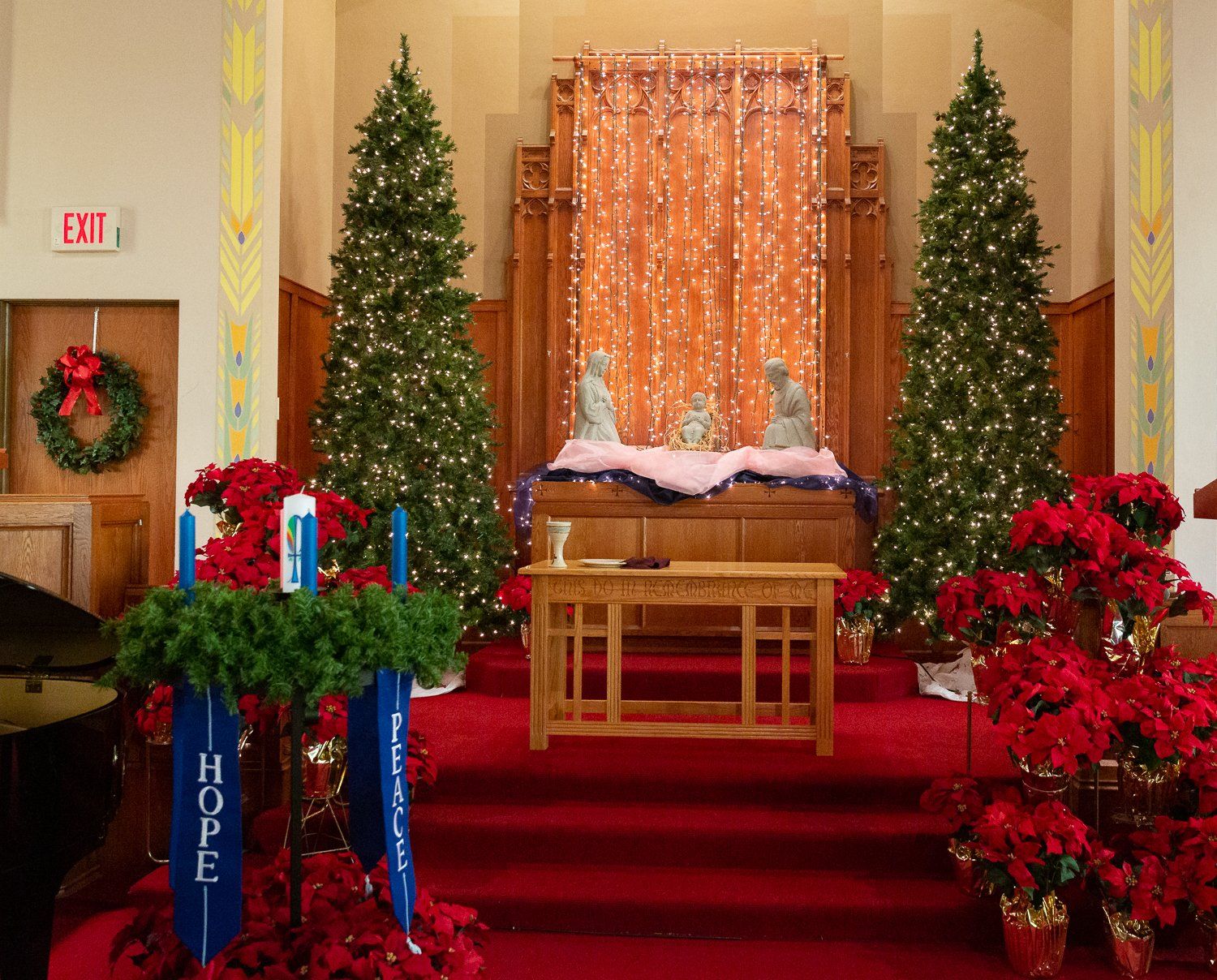 A church is decorated for christmas with trees and flowers