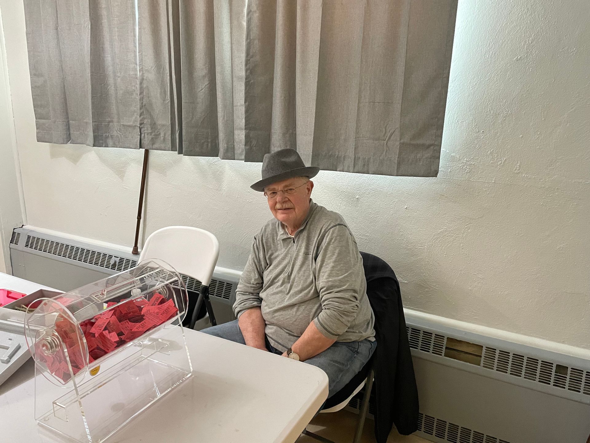 A man in a hat is sitting at a table in front of a window.