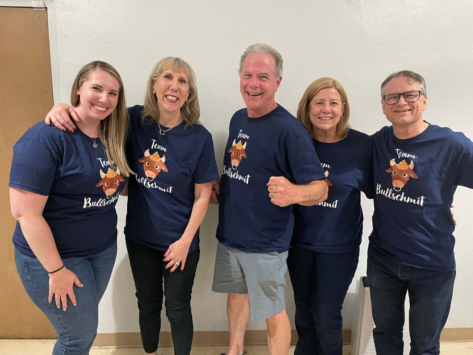 A group of people wearing blue shirts with a bull on them are posing for a picture.