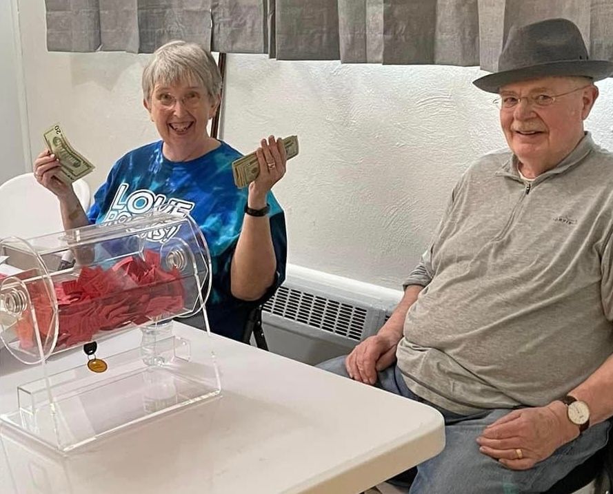A man and a woman are sitting at a table holding money.