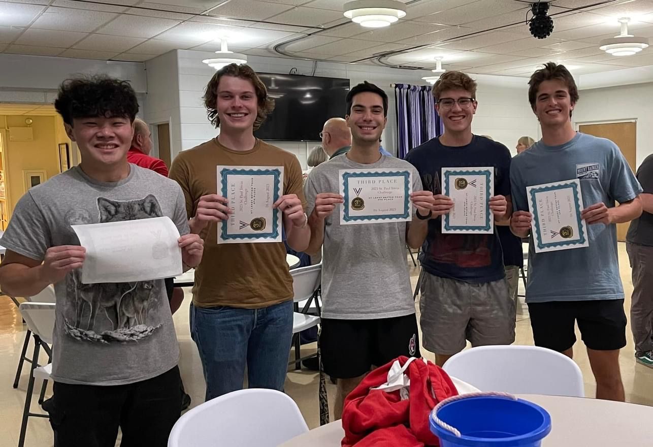 A group of young men are standing around a table holding certificates.