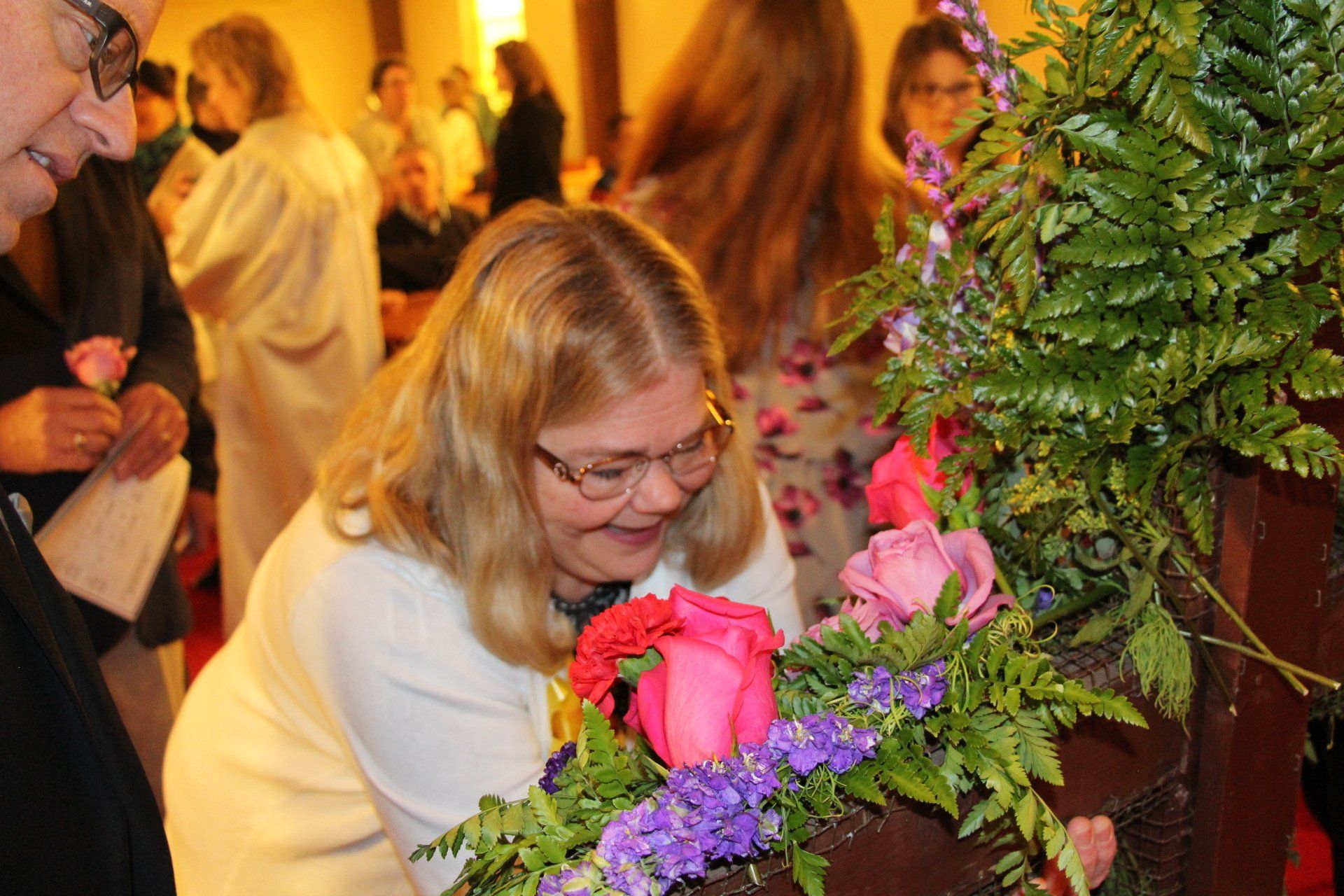 A woman is smelling flowers in a church.