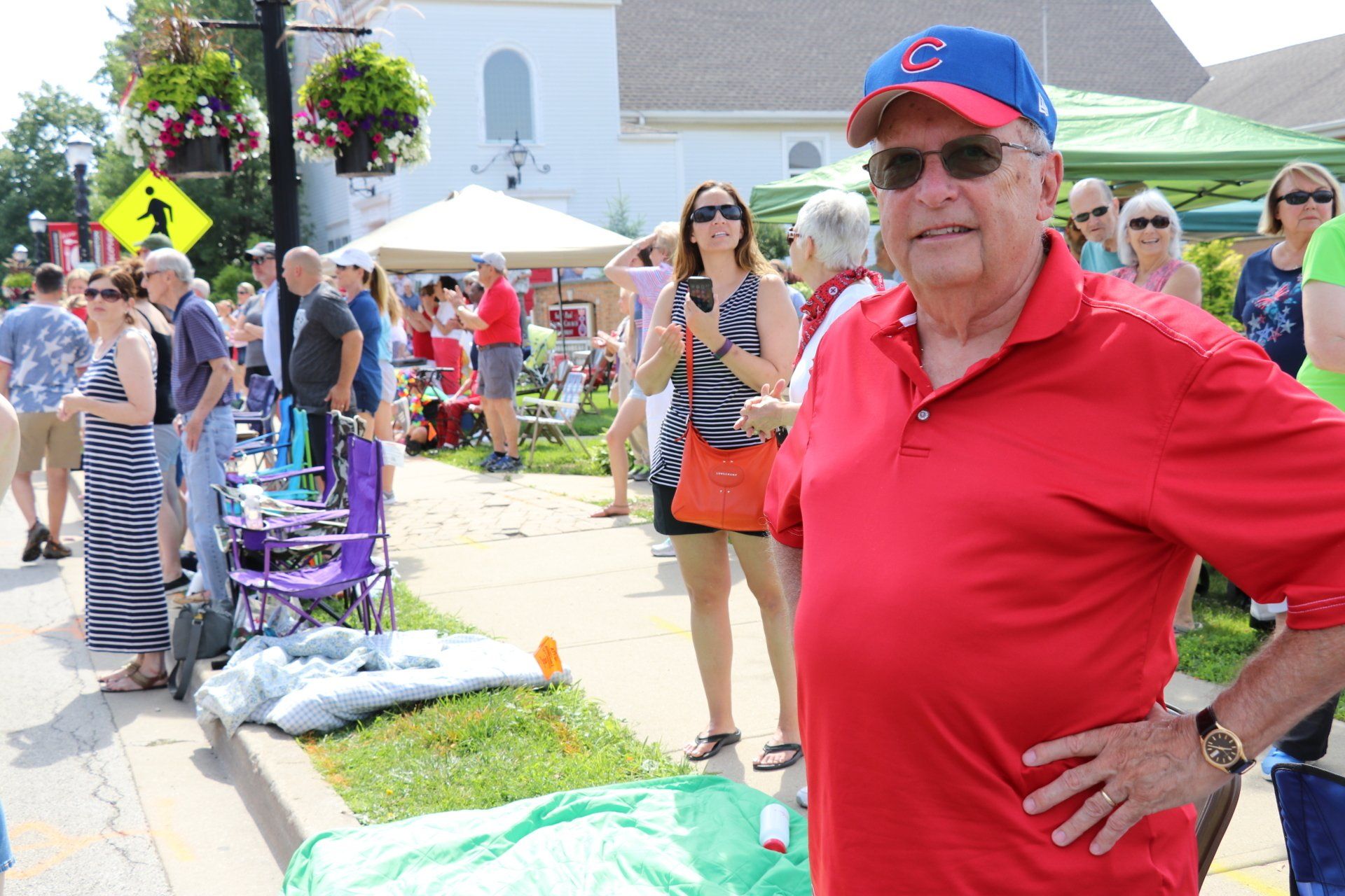 A man in a red shirt and blue hat is standing in front of a crowd of people.