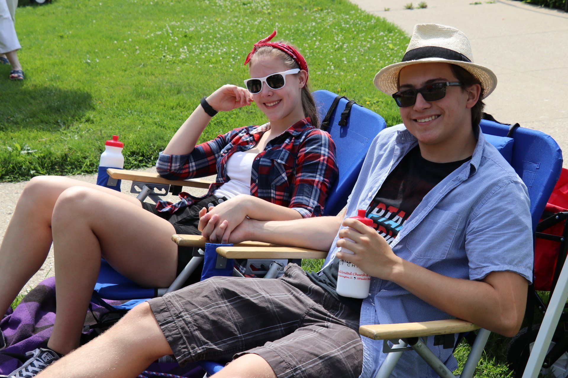 A man and a woman are sitting in folding chairs in a park.