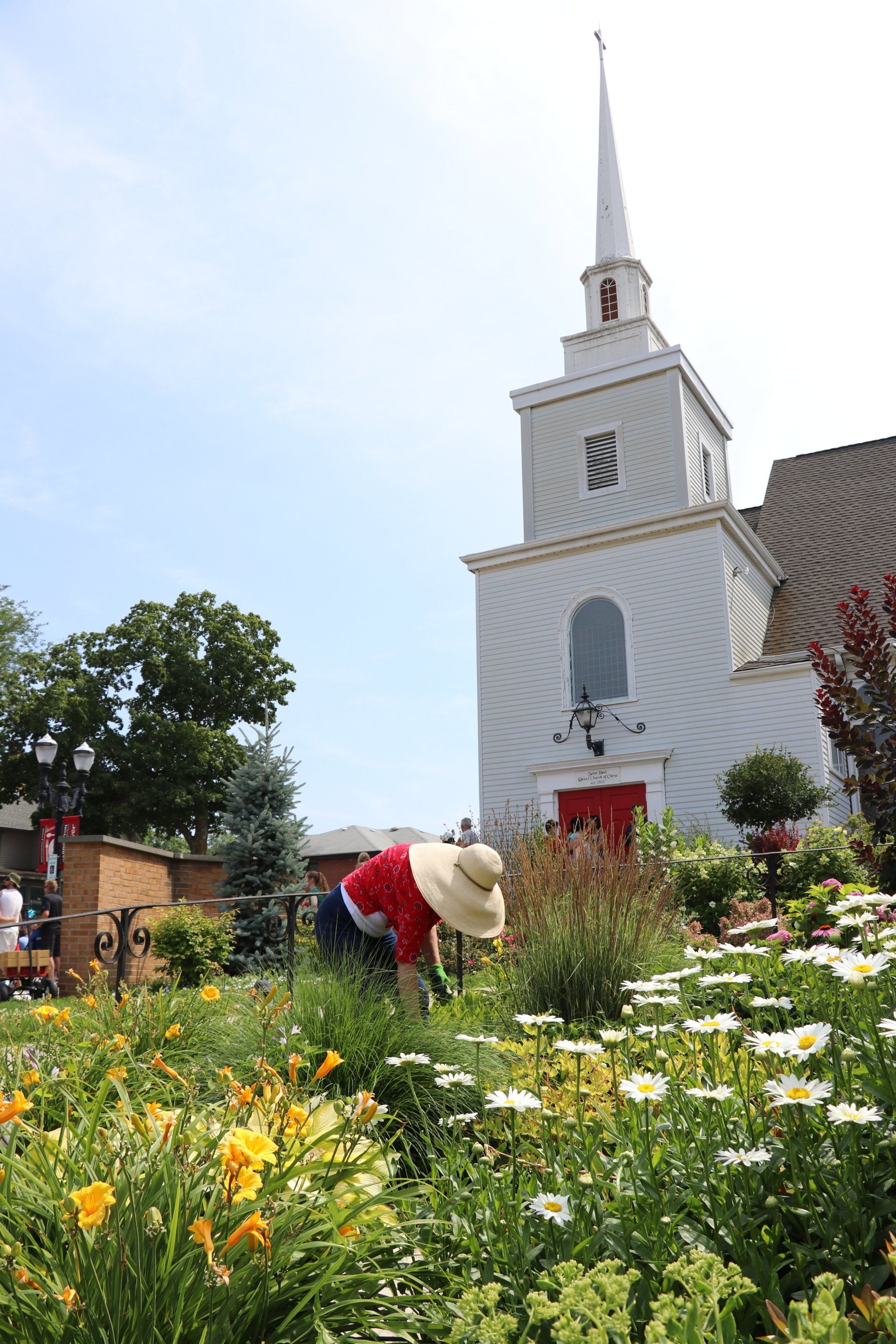 A woman is working in a garden in front of a church.