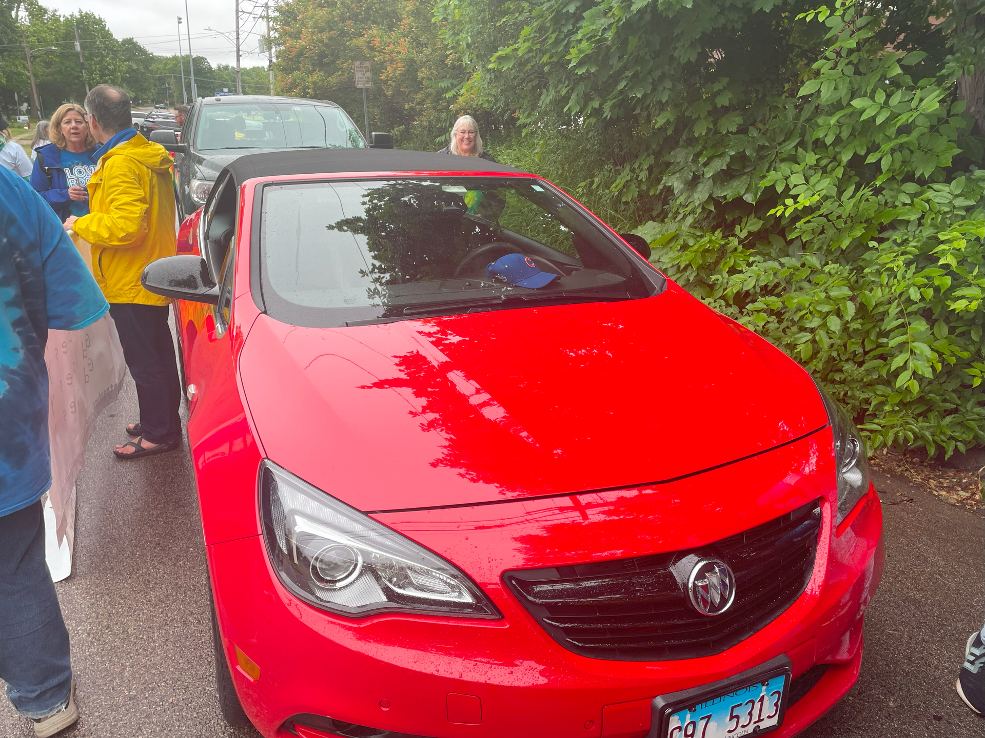 A red buick convertible is parked on the side of the road