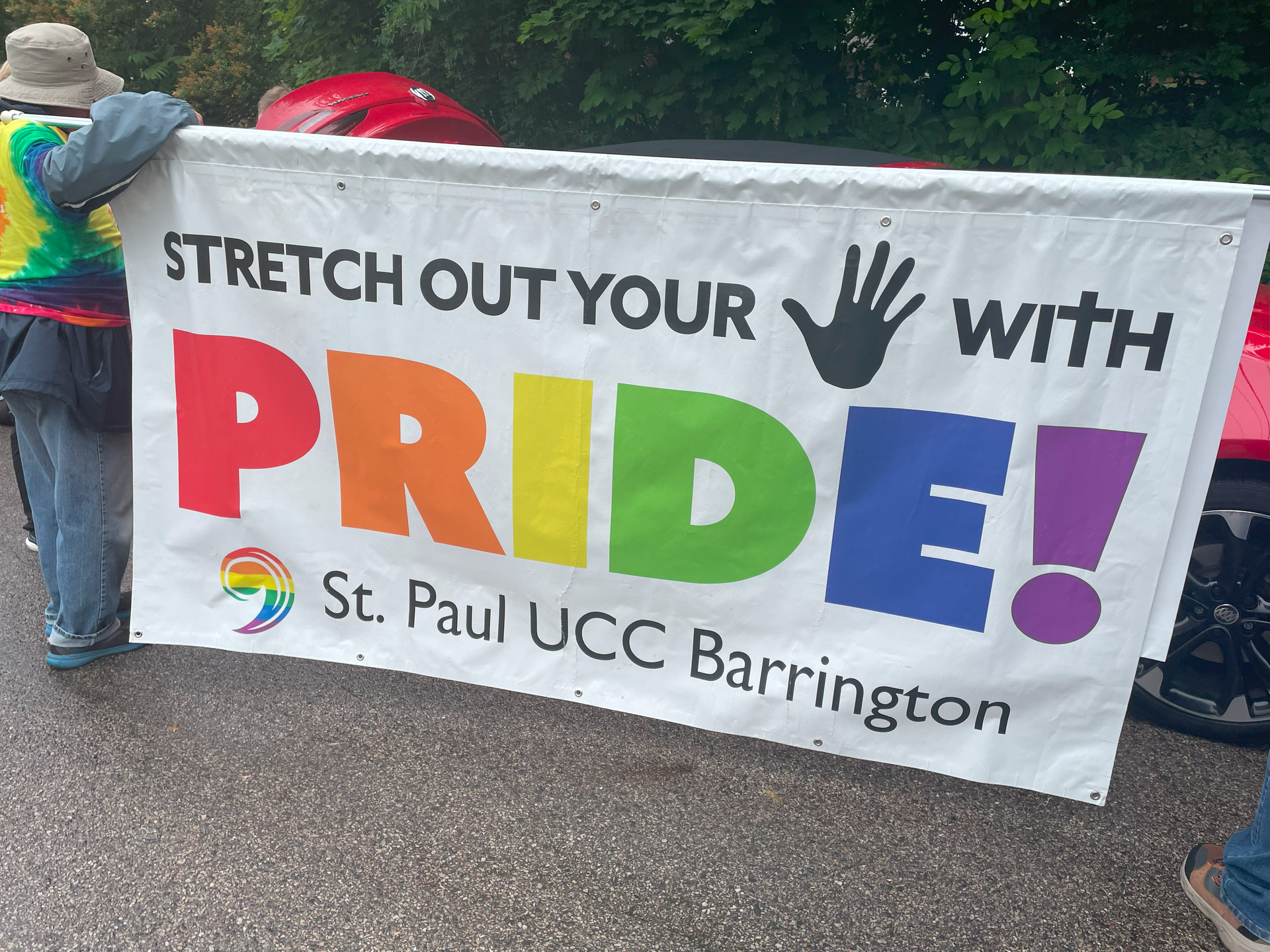 A person is holding a banner that says stretch out your hand with pride