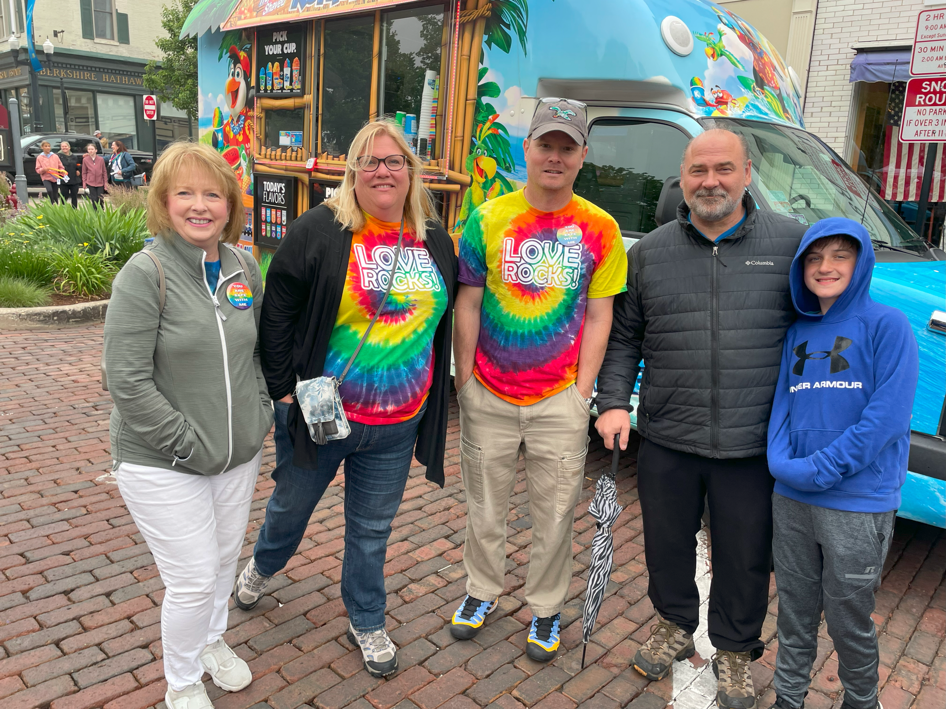 A group of people are posing for a picture in front of an ice cream truck.