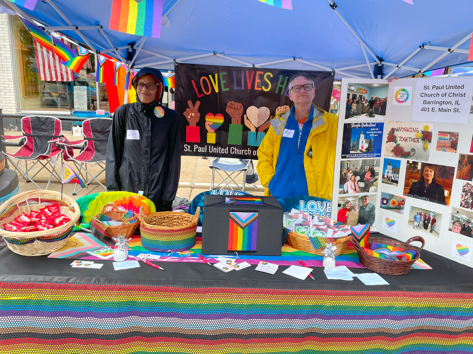Two people are standing behind a table with a sign that says `` love lives ''.