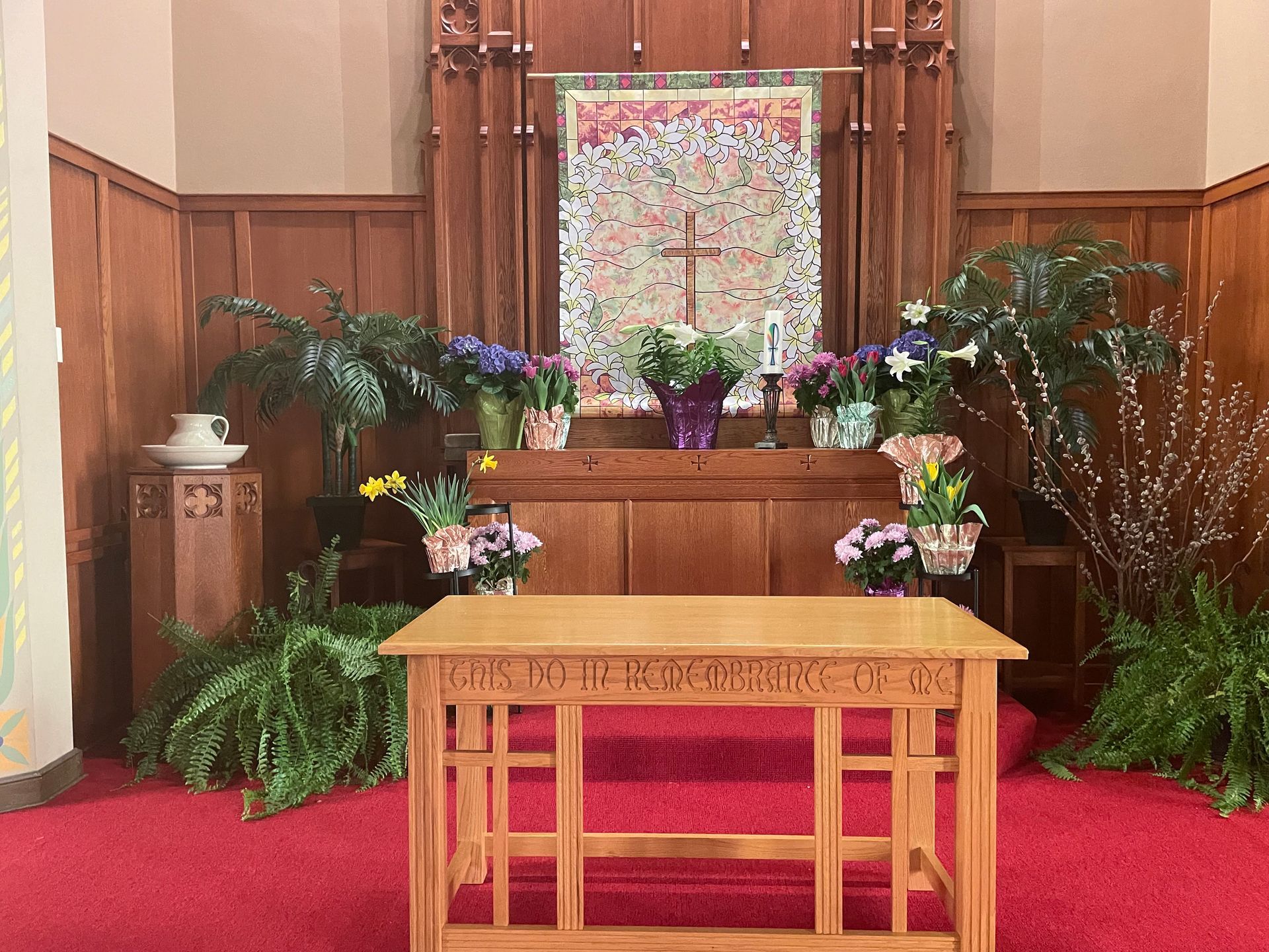 A wooden altar in a church surrounded by flowers and plants.