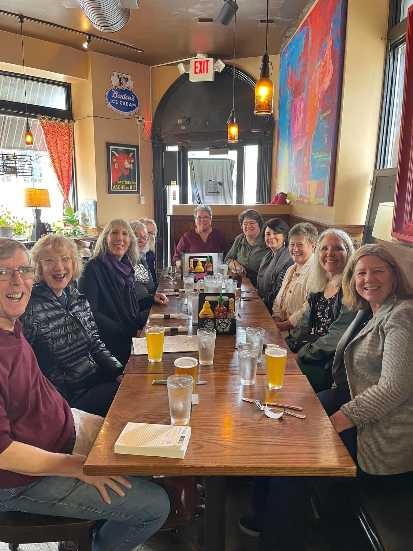 A group of people are sitting at a long table in a restaurant.