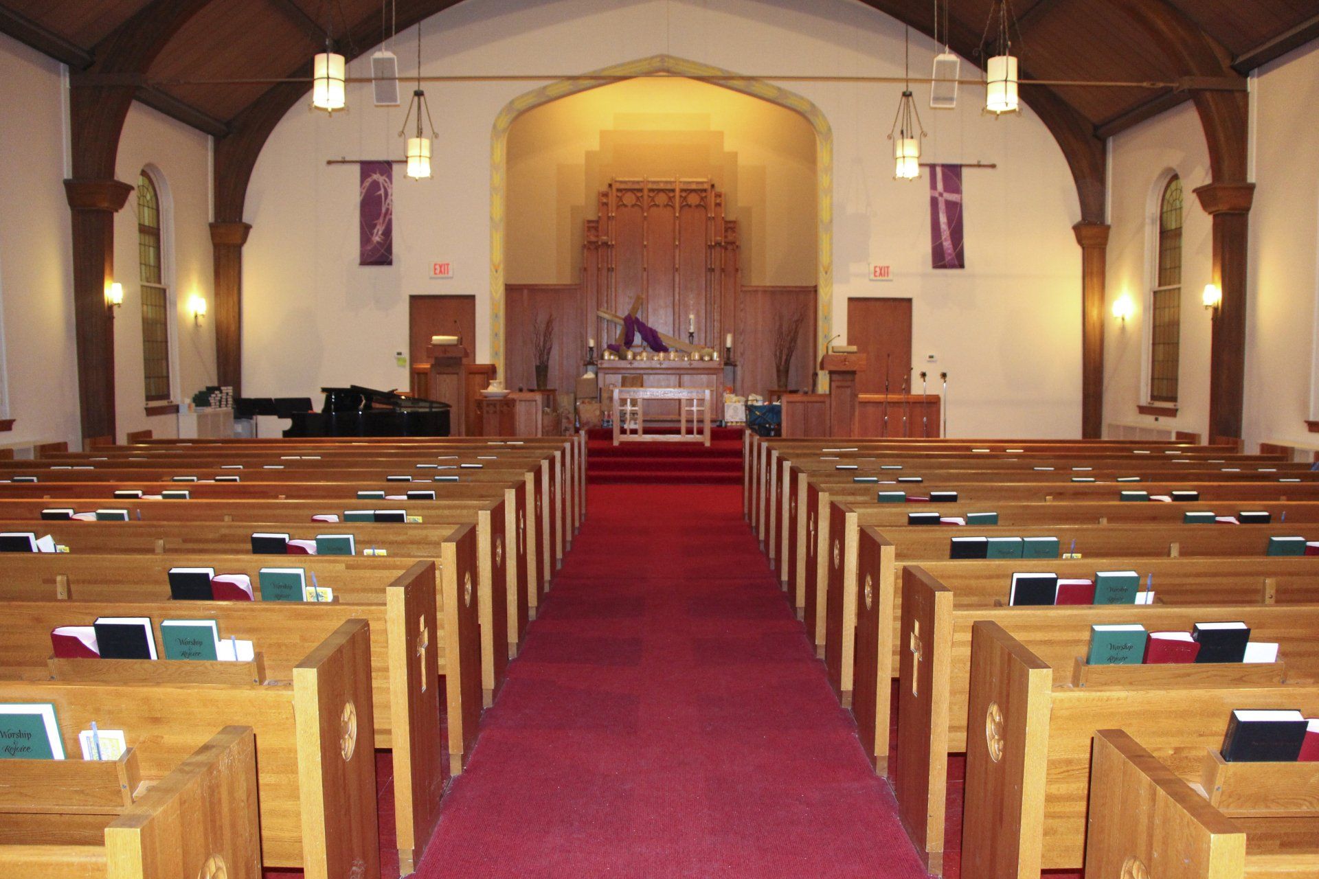 A church with rows of wooden benches and a red carpet