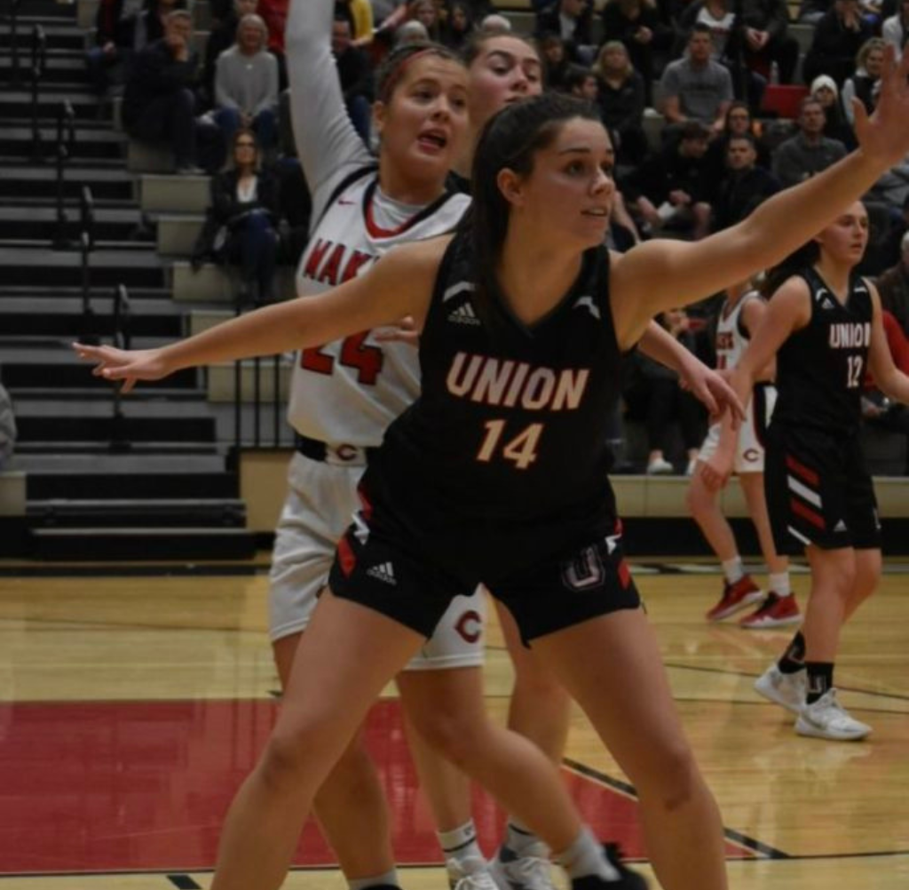 Basketball players in action, Union player in black jersey defending, other players in the background, indoors.