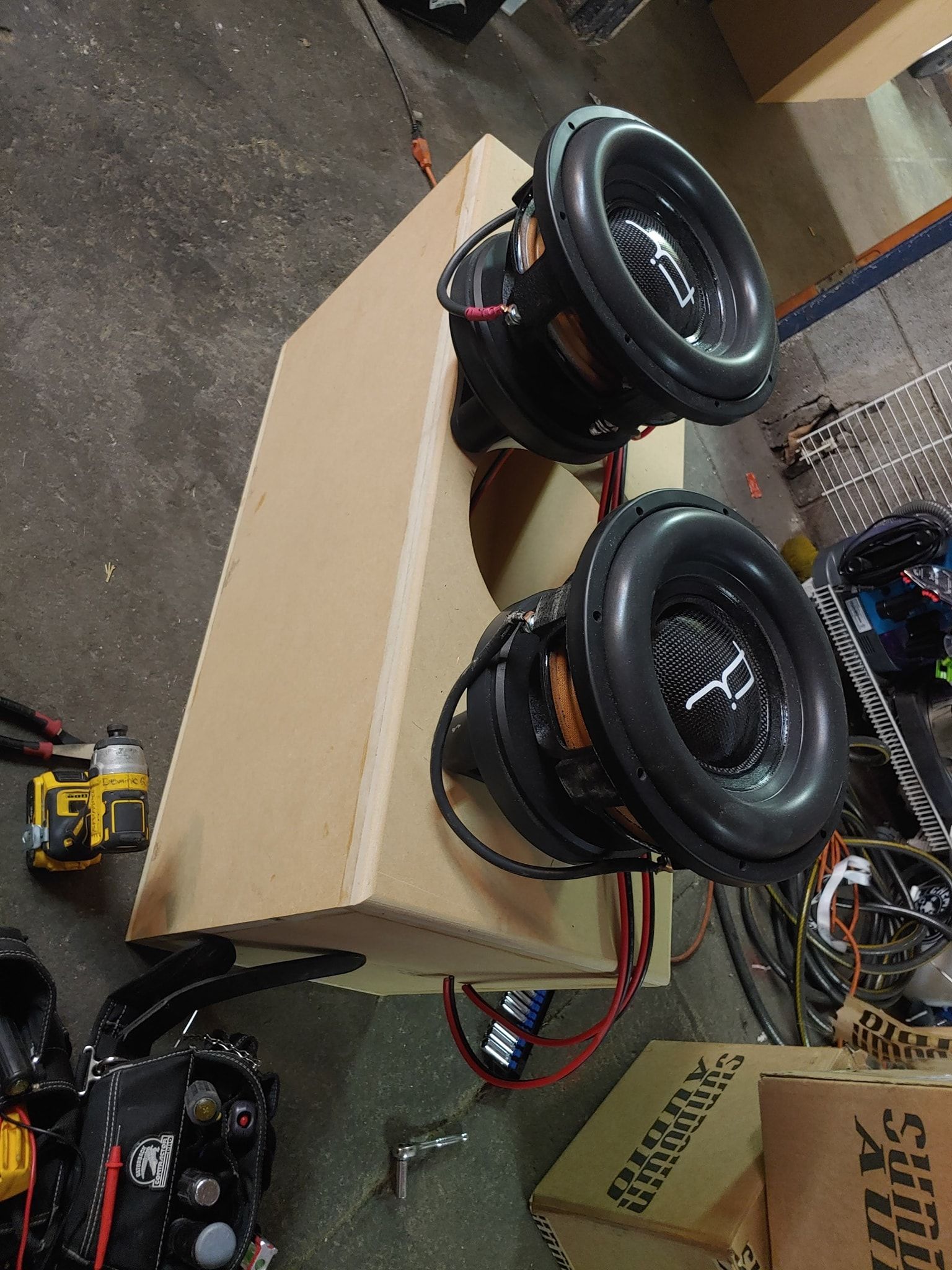 Two car subwoofers installed in a tan rectangular box.