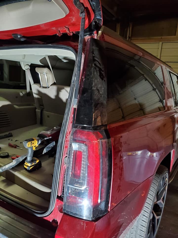 Red SUV with open rear hatch, a taillight is visible, tools inside.
