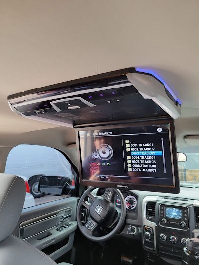 A vehicle interior showing a ceiling-mounted entertainment system with a screen displaying a menu.