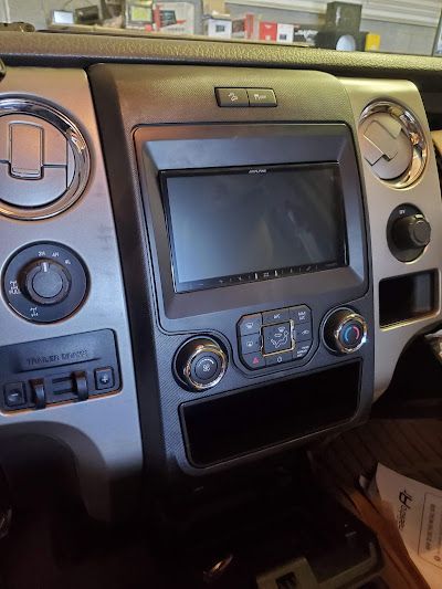 Dashboard of a Ford truck with a large central touchscreen display, silver and black accents, and climate control knobs.