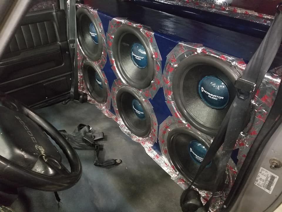 A truck interior modified with six large subwoofers, surrounded by foil and a blue panel.
