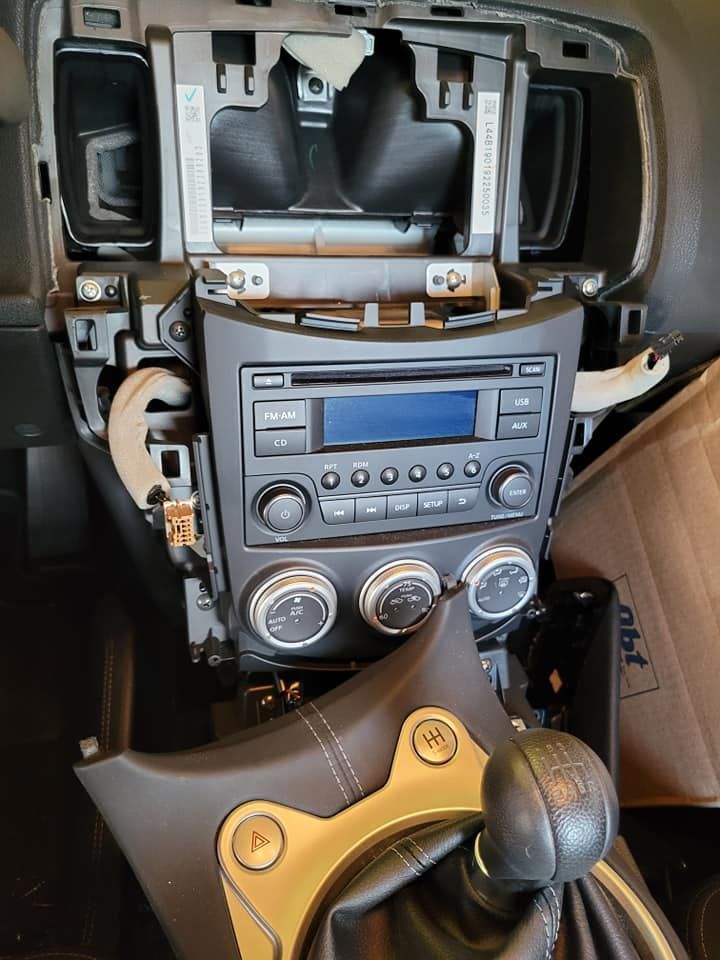 Interior view of a car dashboard with the radio and climate controls exposed. A manual gear shift is visible.