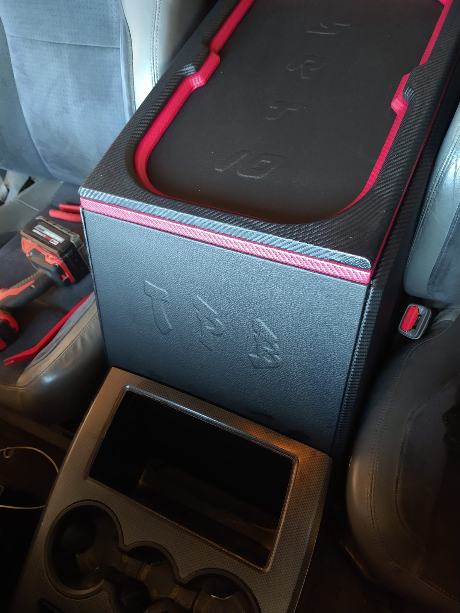Black car subwoofer with red trim, a dashboard panel, and car interior.
