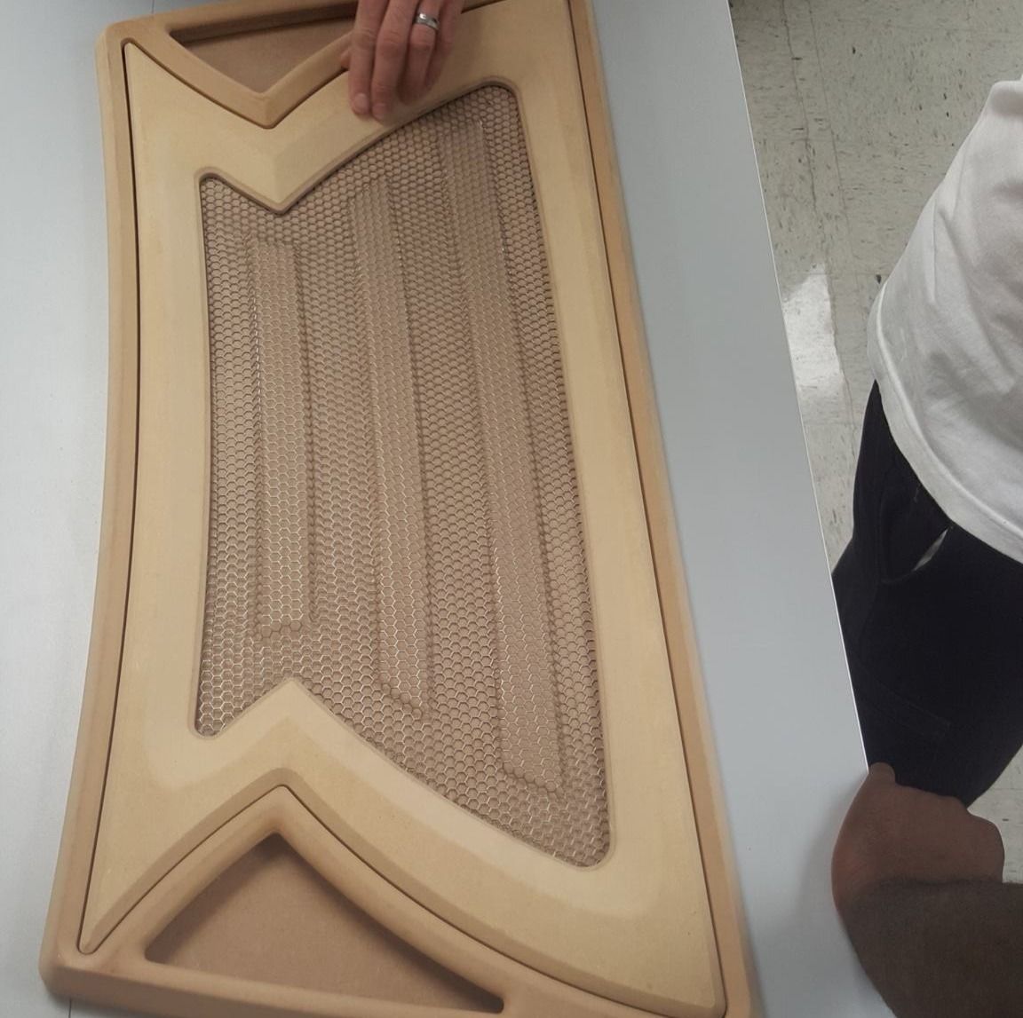 A person holding a wooden cat scratching board with a woven center.