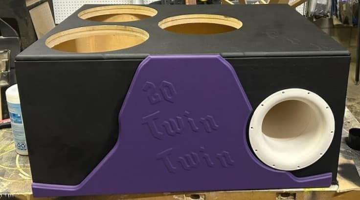 Black and purple custom car audio subwoofer box with four speaker holes and a port. The box has 