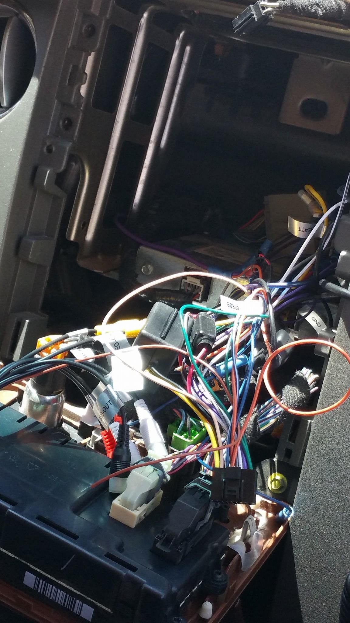Car dashboard interior with exposed wiring. A radio is visible, with various colored wires and connectors surrounding it.