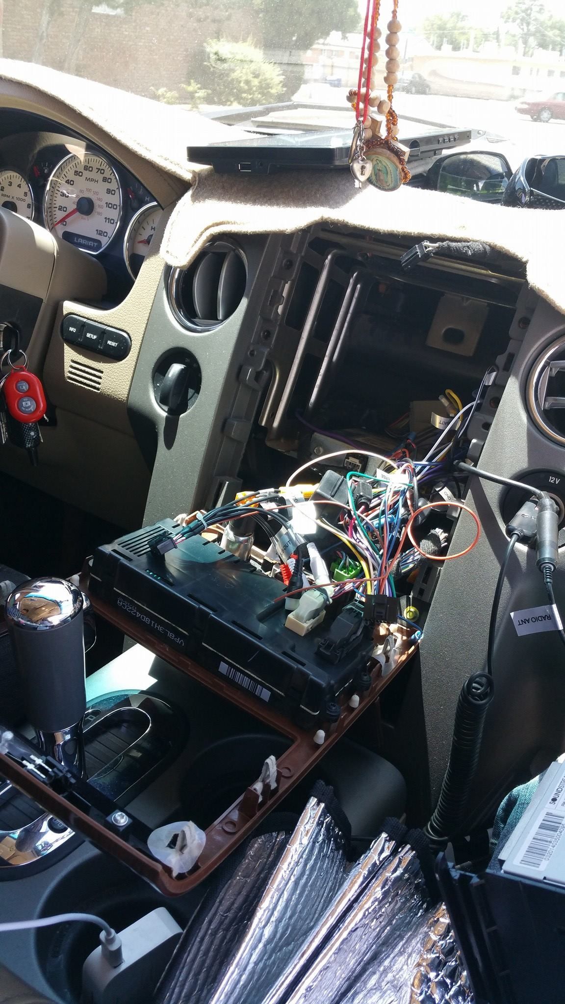 Car dashboard with exposed electronics; a radio or navigation system is disassembled. 