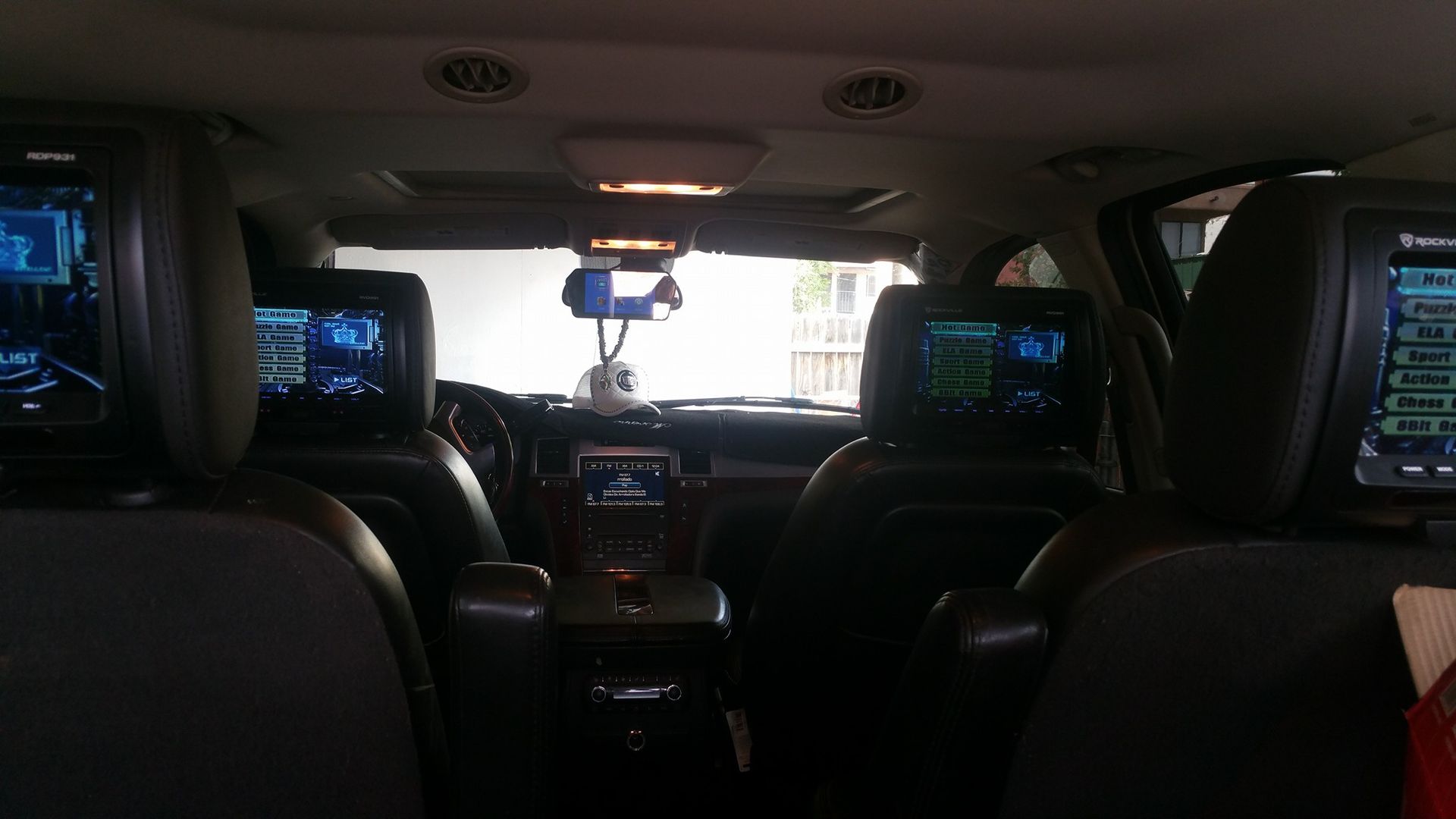 Interior of a car with three screens displaying navigation or entertainment, built into the headrests. 