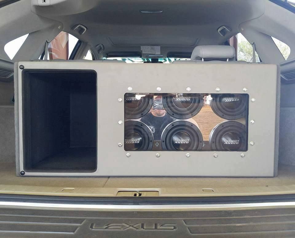 A large custom subwoofer box with six speakers installed in the trunk of a Lexus SUV. Gray box, black speakers.