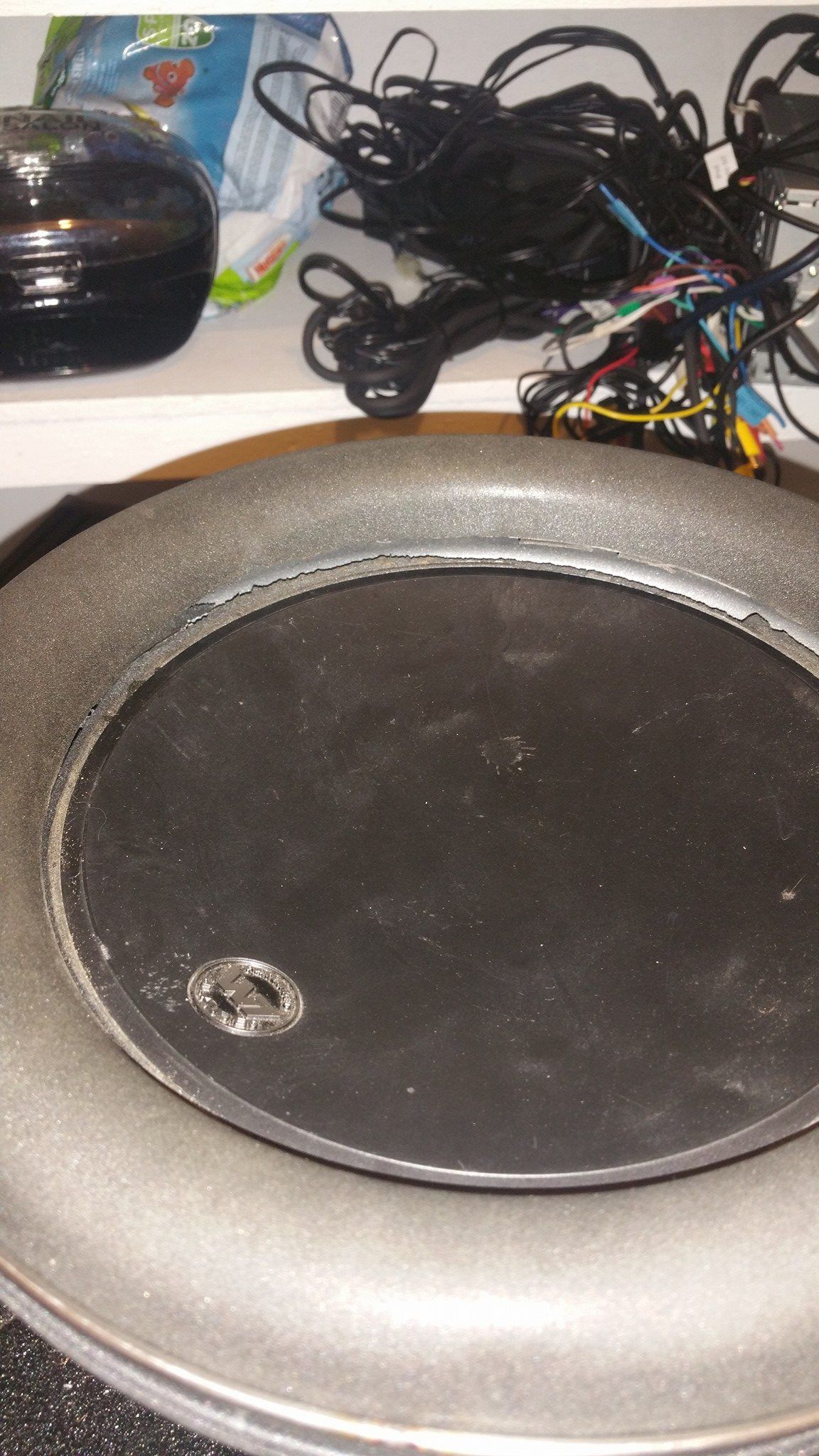 A close-up view of a black speaker with a dark center, surrounded by a silver glittery border.