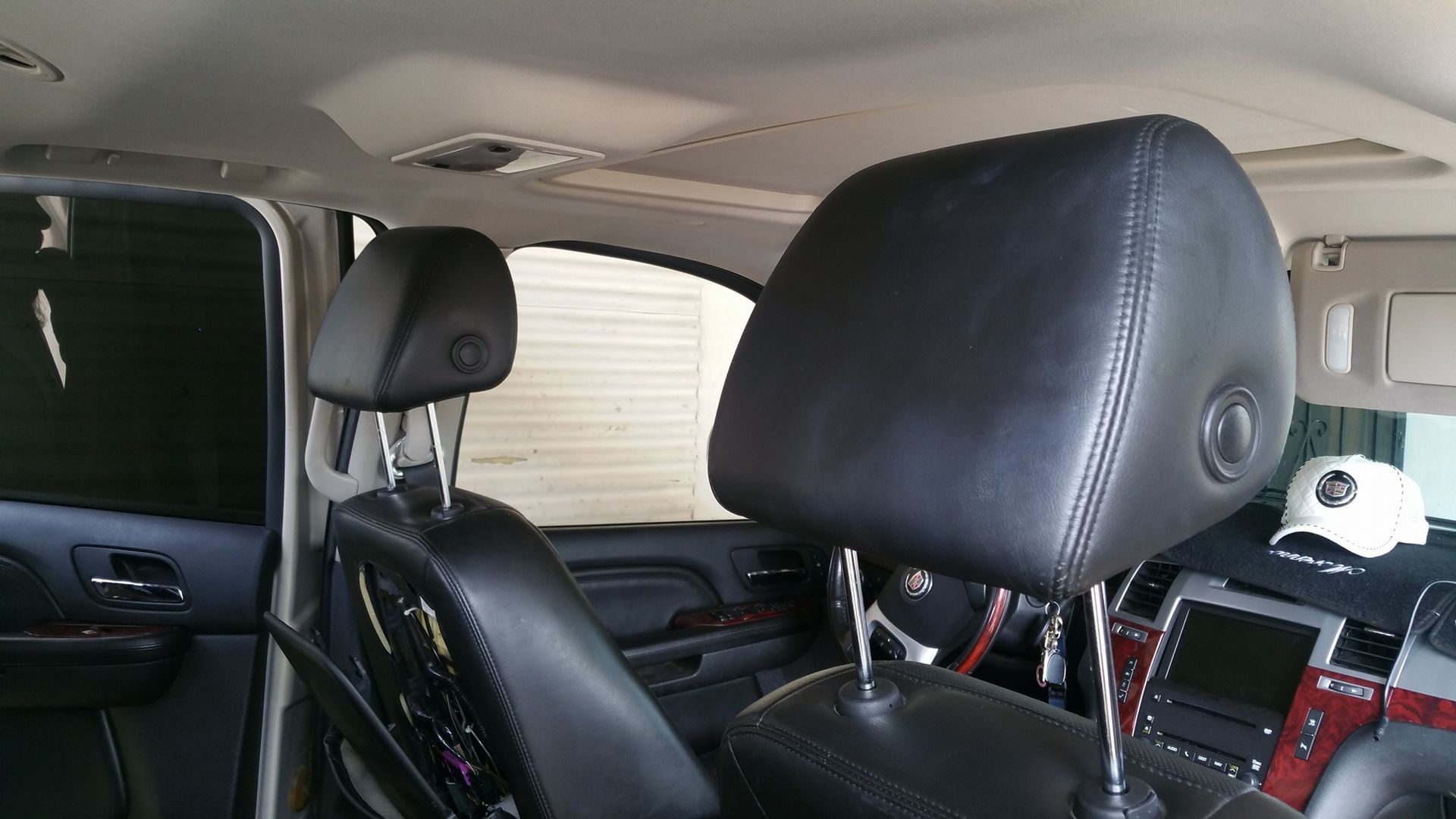 Interior of a car, featuring two black leather headrests. The dashboard and window are visible.