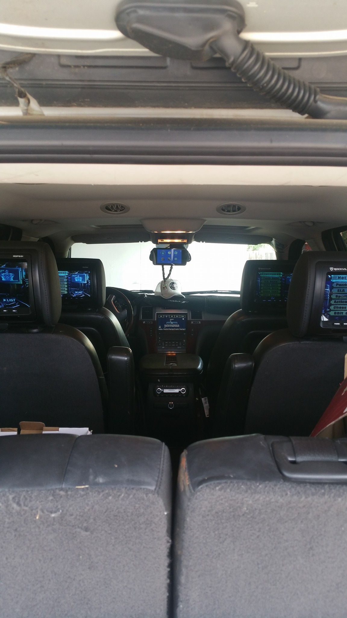 Interior view of an SUV's back seat, showing two headrest screens, a console, and a rearview mirror.