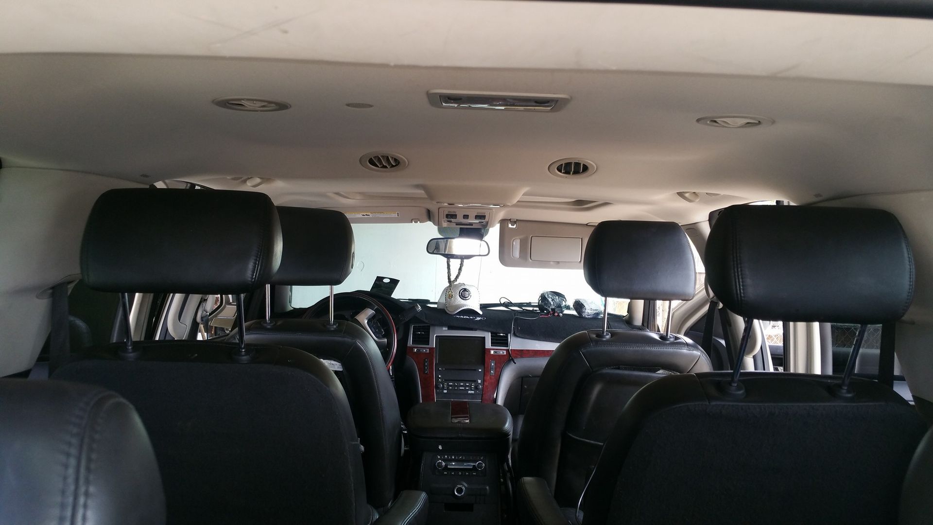 Interior view of a black SUV, showing rear seats and headrests. Details include ceiling vents, a mirror, and center console.