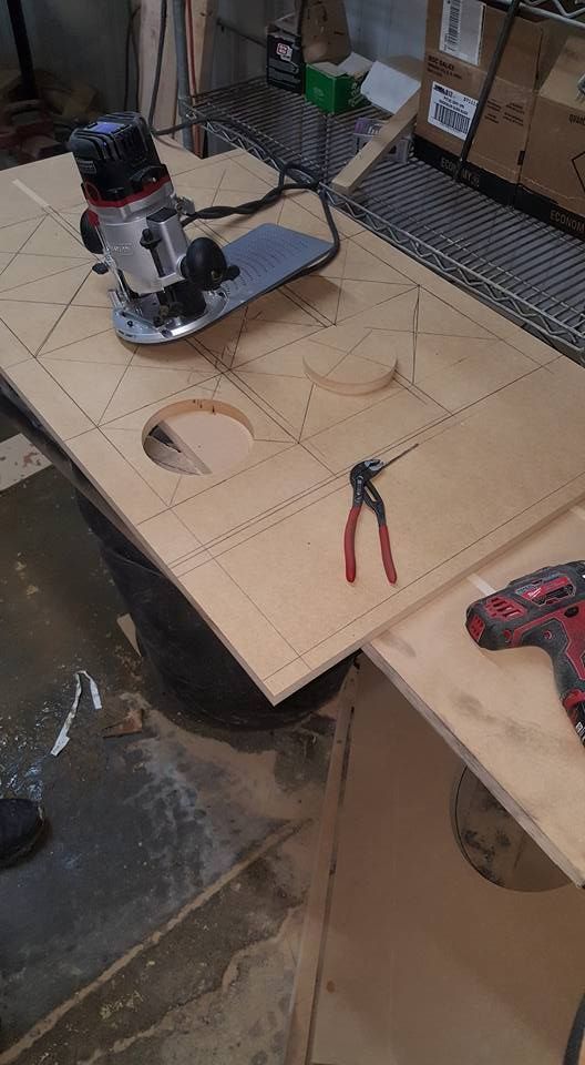 A router cutting wood, likely for a project, with tools nearby on a work surface.