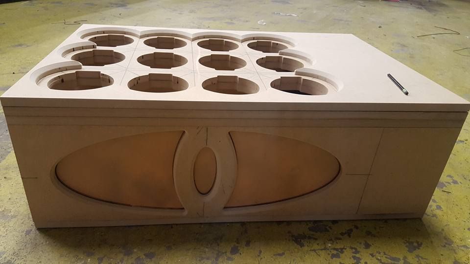 Wooden box with circular cutouts on top and an oval design on the front.