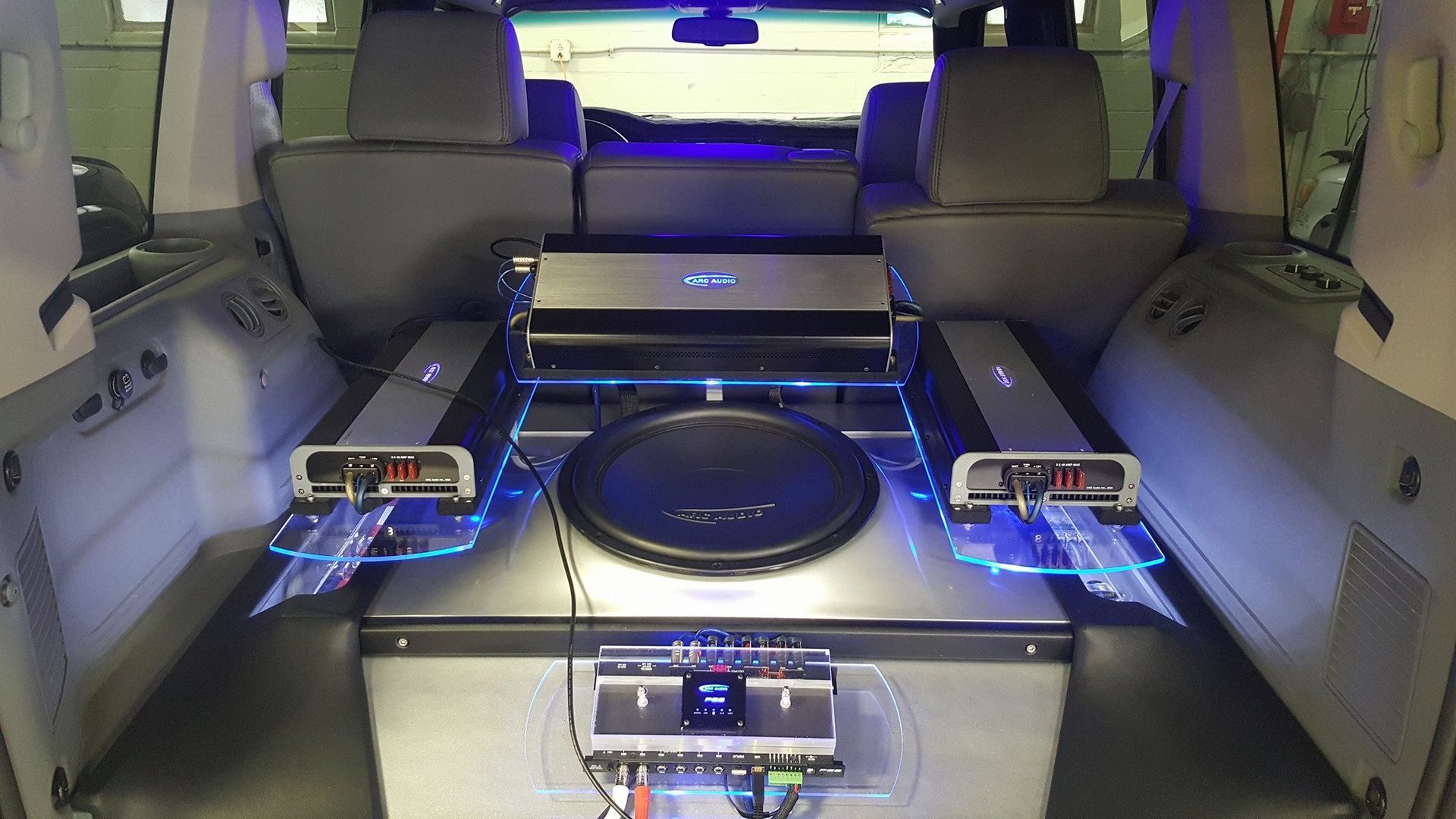 Interior of a car with a custom audio system. Large subwoofer, amplifiers with blue lighting.