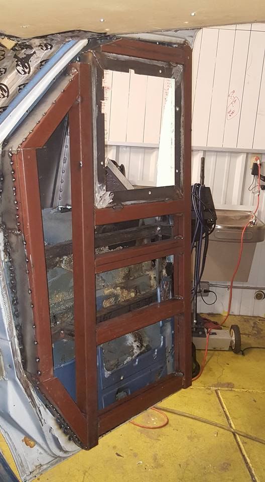 A rusty, rectangular metal frame, likely for a machine or structure, in a workshop setting.