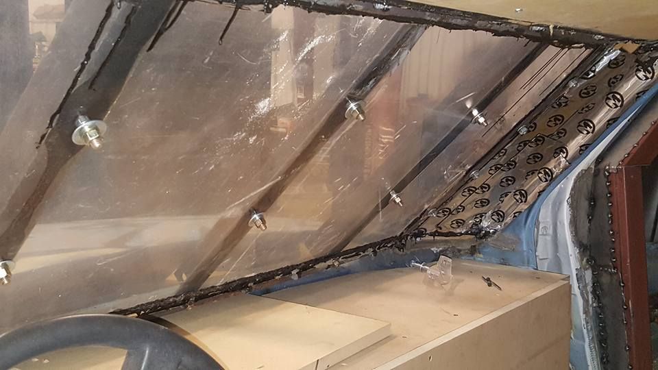 Interior of a vehicle with a plastic windshield installed, the dashboard visible below.