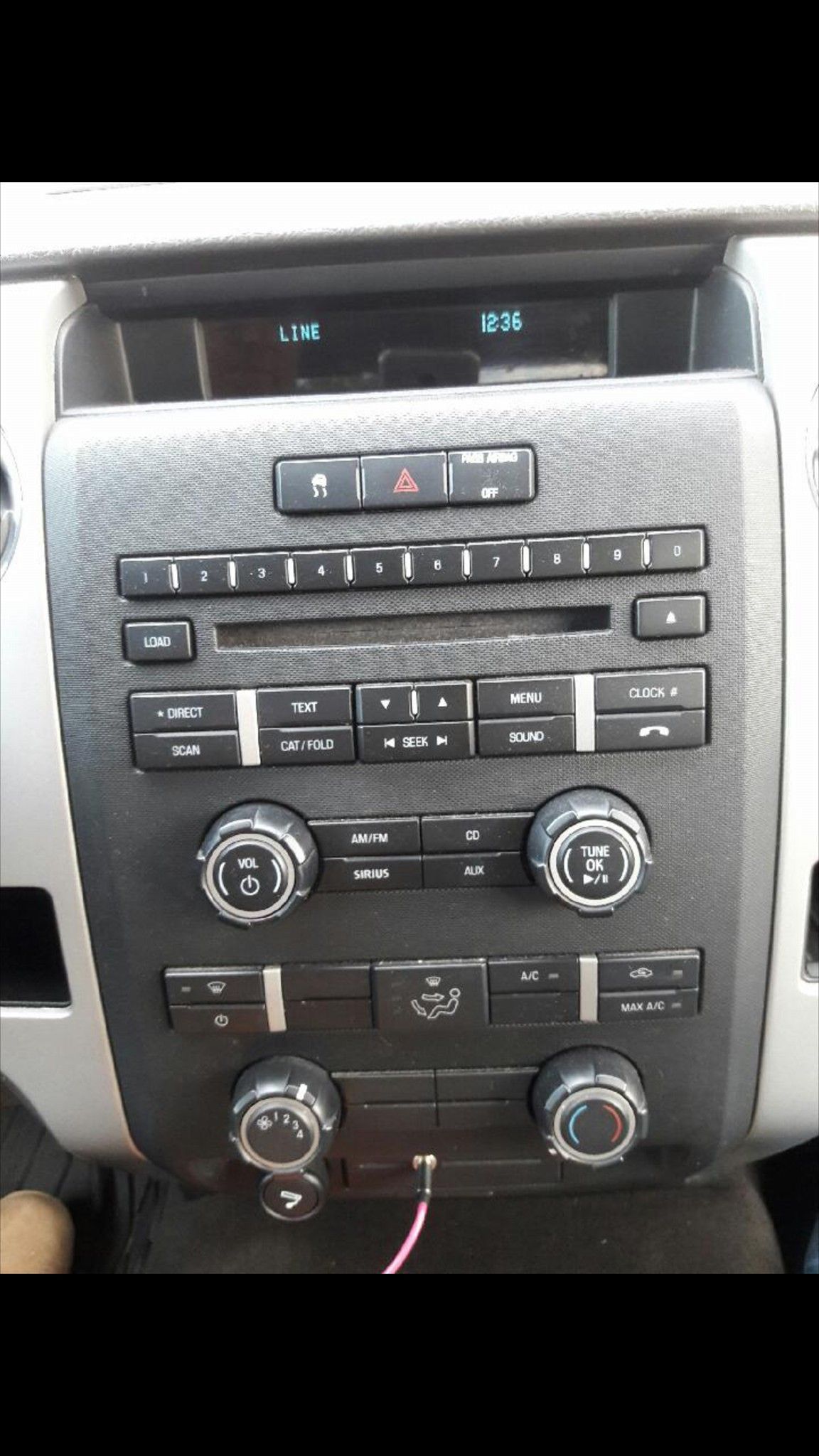 Car dashboard with a radio, climate controls, and a display screen, all in black and silver.