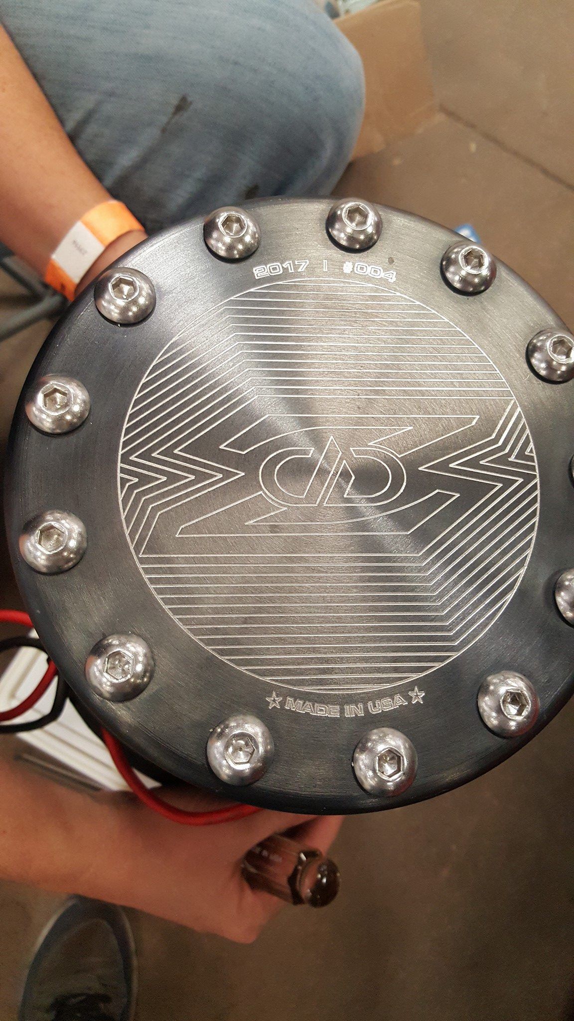 Close-up of a black fuel cell top with a detailed etched design and silver bolts, held by a person.