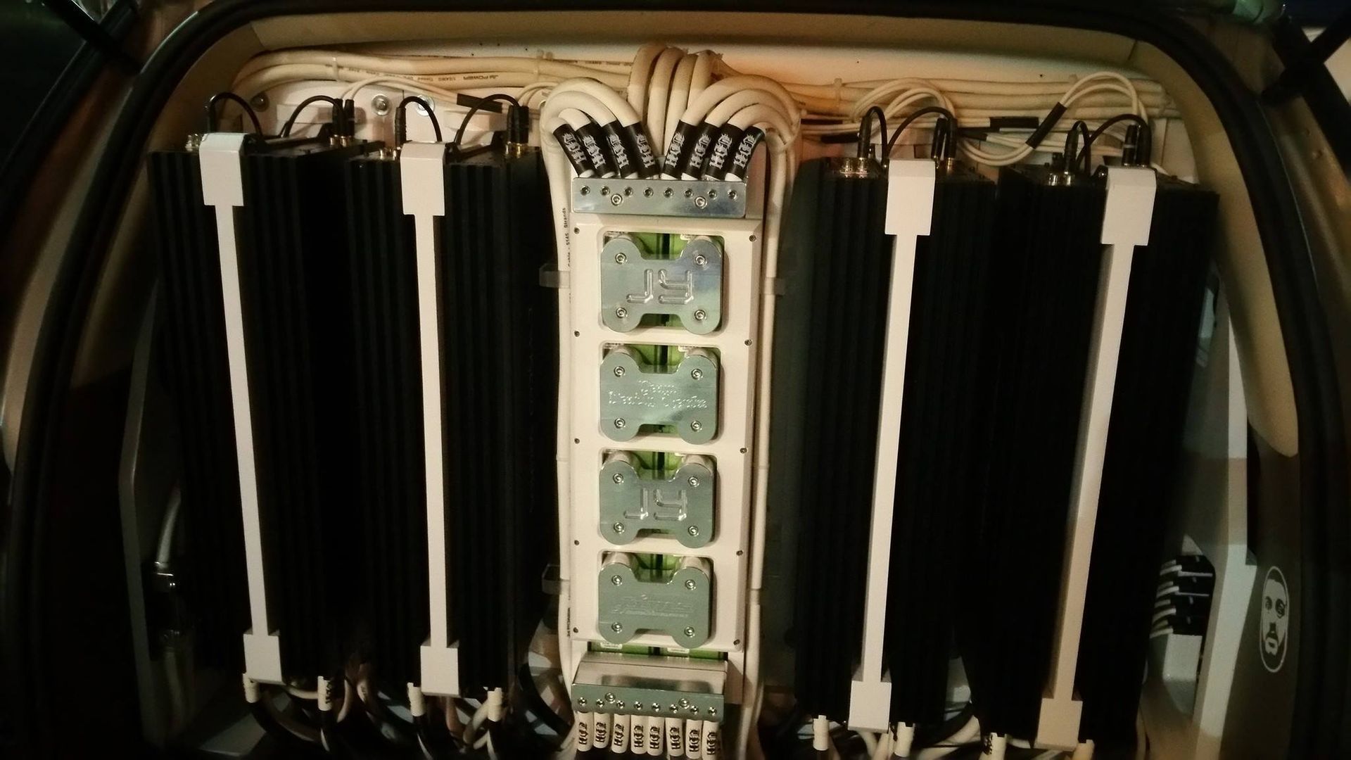 Car audio setup with multiple black amplifiers mounted on white panels inside a vehicle. Wiring is visible.
