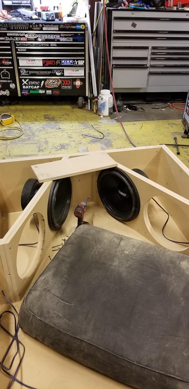 A partially built car audio subwoofer enclosure with three speakers. 
