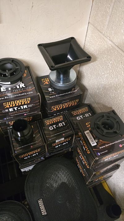 Pile of black car audio speakers and components, including boxes, horns, and tweeter drivers.