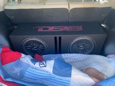 Two black subwoofers in a box with red 