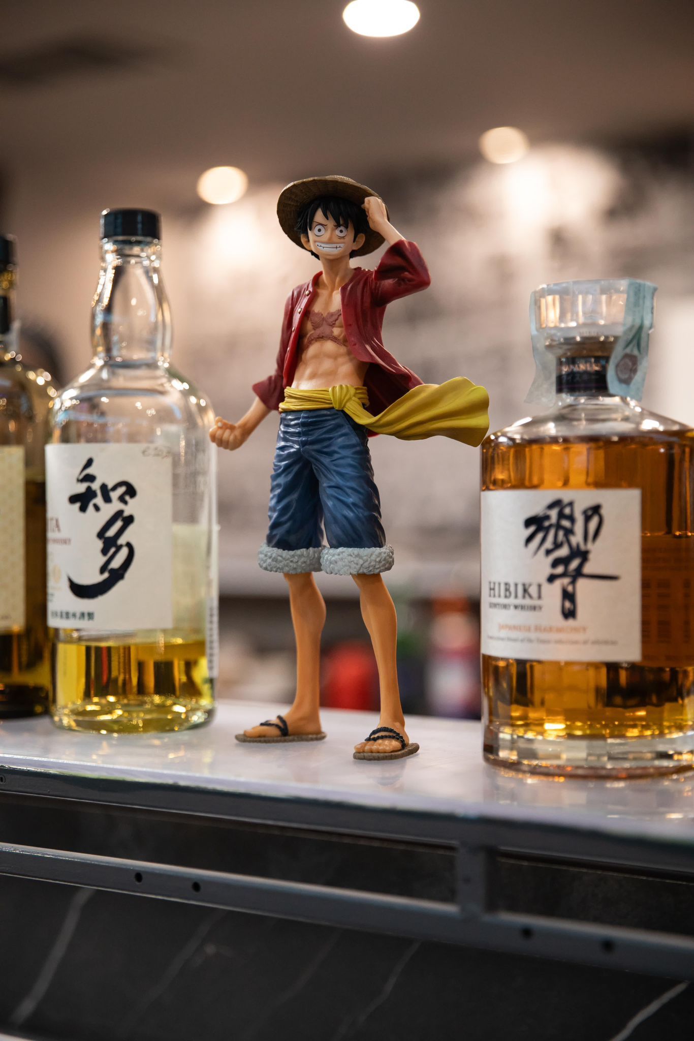 Una statuetta di Monkey D. Luffy in piedi accanto a una bottiglia di whisky.