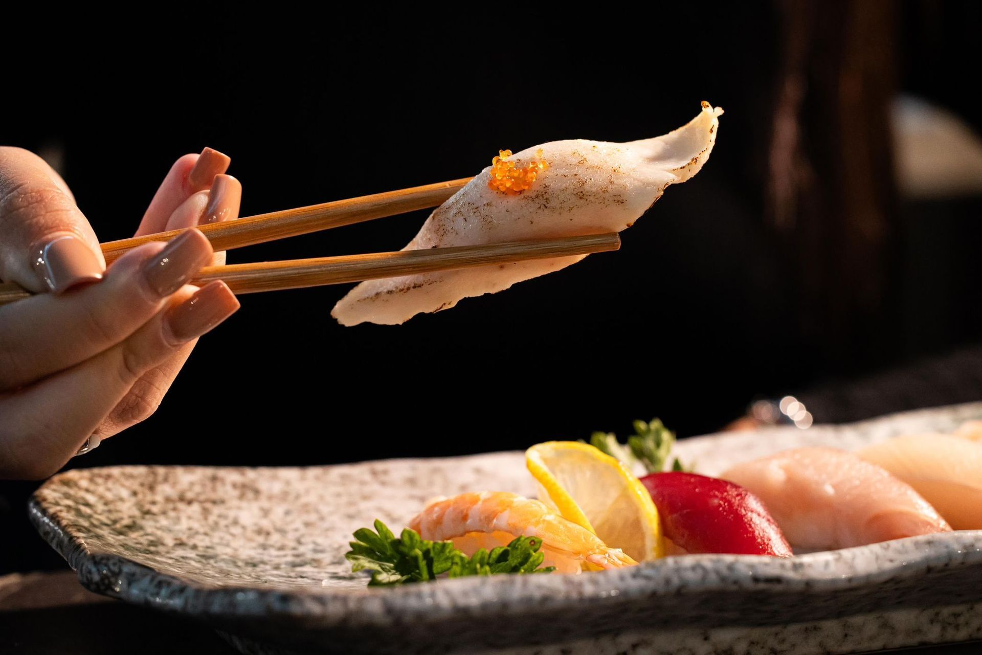 Una persona tiene le bacchette sopra un piatto di cibo.