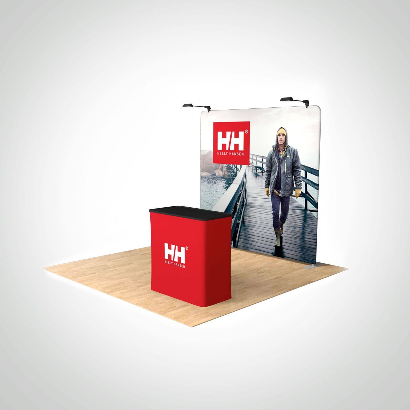 Trade show booth with a red counter and a backdrop featuring the Helly Hansen logo and a person walking on a pier.