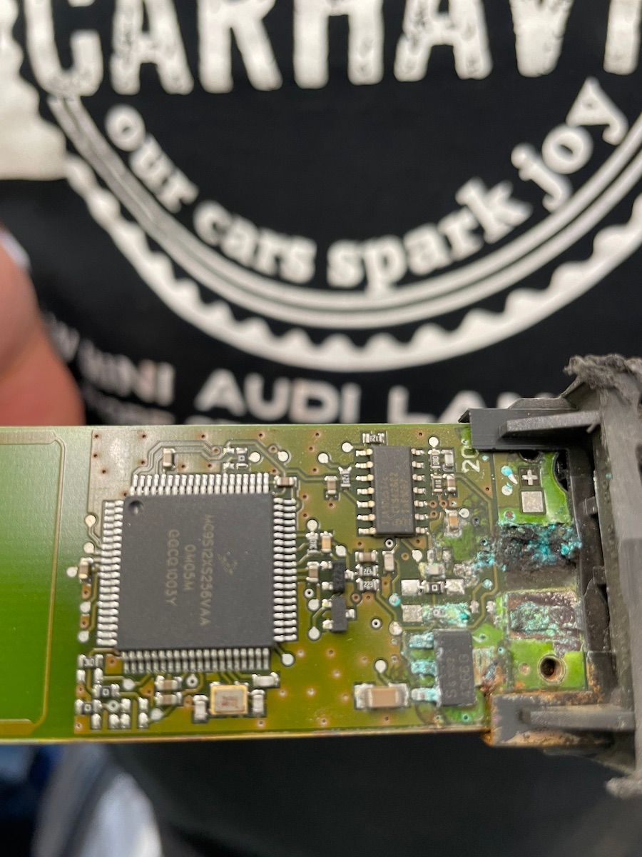 A person is holding a motherboard in front of a logo that says our cars spark joy.